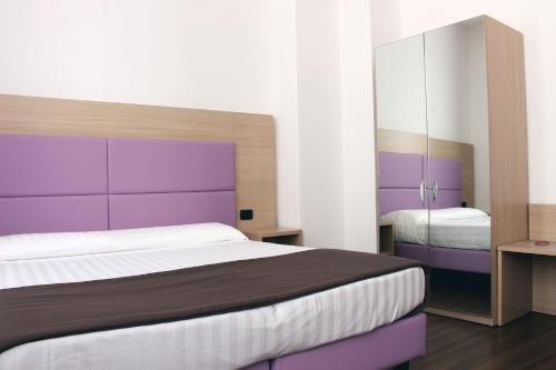 a bedroom with a large bed with a purple headboard at Hotel Esperanza in Florence