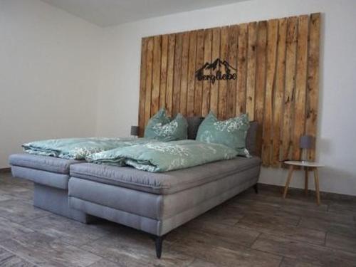 Bett in einem Zimmer mit einer Holzwand in der Unterkunft Ferienwohnung Haus Redi in Sasbach in der Ortenau