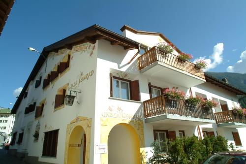 a white building with balconies and flowers on it at Hotel Conrad in Scuol