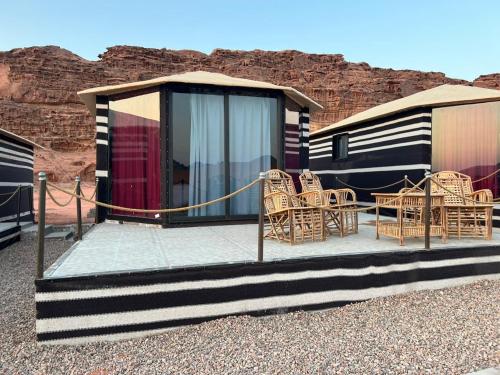 a cabin with chairs and tables in front of a mountain at Wadi Rum Desert Adventures in Wadi Rum