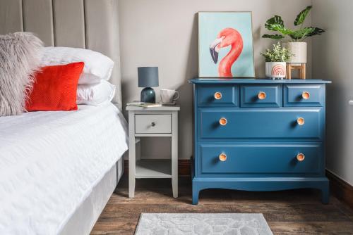 uma cómoda azul com um flamingo vermelho ao lado de uma cama em Doodle Den em Kendal