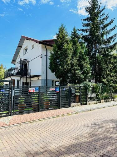 a fence in front of a house with a tree at Apartamenty Pokoje Willa Bielany in Warsaw