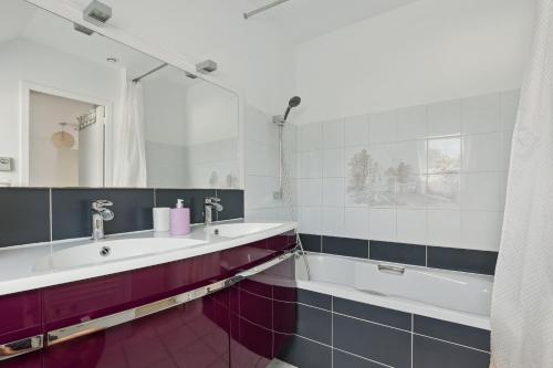 La salle de bains est pourvue d'un lavabo, d'une baignoire et d'un miroir. dans l'établissement Le Lussac - Saint Cyr, à Saint-Cyr-lʼÉcole