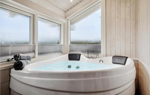 una gran bañera blanca en una habitación con ventanas en Beautiful Home In Harbore With Sauna, en Harboør