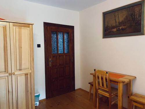 a dining room with a wooden table and a door at Agroturystyka SKALNE in Szczawa