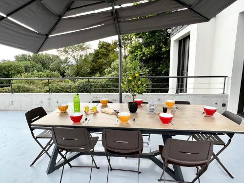 een tafel met stoelen en een parasol op een patio bij La Villa Océane, Elegante, Plages, GR34, 2-8 pers in Clohars-Carnoët