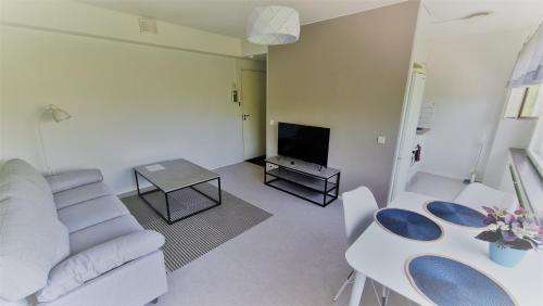 a living room with a couch and a table and a tv at Aparthotel Clock 5 in Kotka