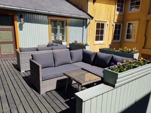 a patio with a couch and a table and flowers at Houmbgaarden in Røros