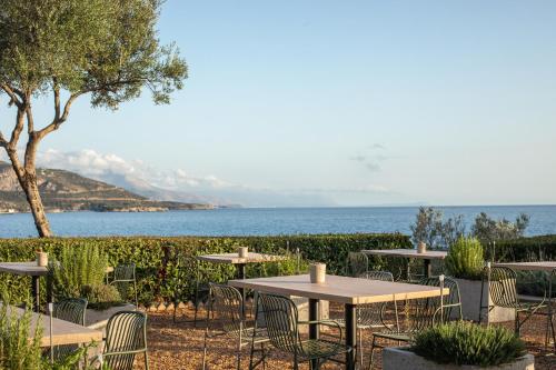 a row of tables and chairs with the ocean in the background at Melitsina Village Hotel in Kardamili