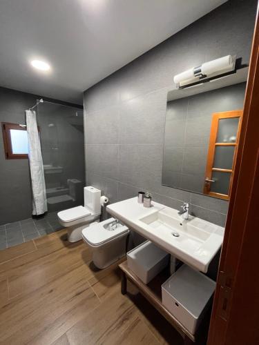 uma casa de banho com 2 lavatórios, um WC e um espelho. em Casa Canaria em Telde