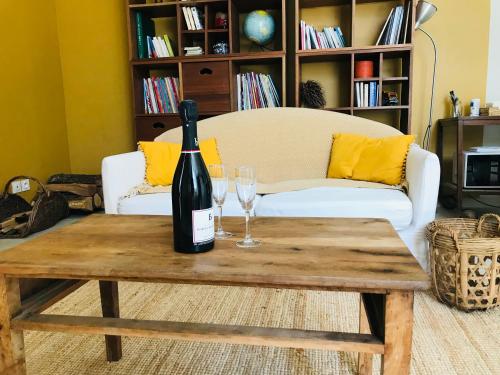 uma garrafa de vinho numa mesa de madeira com dois copos de vinho em ferme st pierre suite, piscine, clim, repas, cheminée em Chabeuil