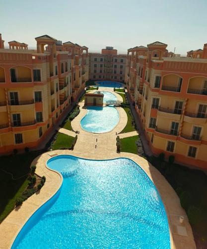 an aerial view of two swimming pools between buildings at منتجع الياقوتة الحمراء in Hurghada