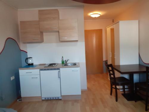 a kitchen with white cabinets and a table and a dining room at Hotel das rot in Burgkunstadt