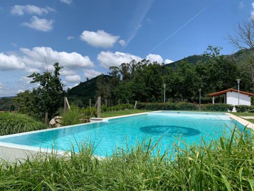 ein Schwimmbad in einem Garten mit Bergen im Hintergrund in der Unterkunft Hotel Nande in Nieves