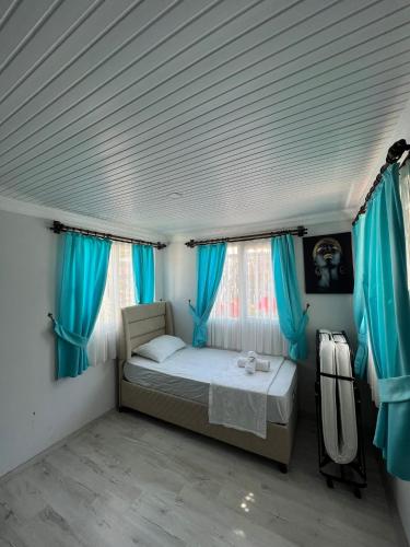 a small bedroom with blue curtains and a bed at ZEYOS LODGE HOTEL&RESTAURANT in Kumluca