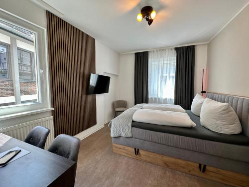 a bedroom with a bed and a table and a television at Hotel Emilia in Würzburg