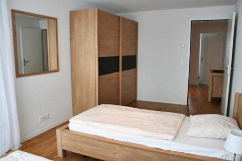 ツークにあるNest - Nordstrasse 9のベッドルーム1室(ベッド1台付)、木製キャビネットが備わります。