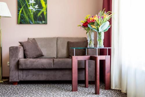 a living room with a couch and a table with flowers on it at Saaremaa Rannahotell ' Beach Hotel in Mändjala