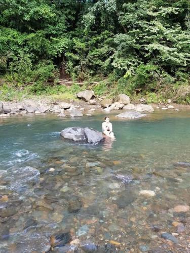 a person sitting on a rock in a river at Luxury Villa Carao - Serene Amazing Views at Finca Chilanga in San Mateo