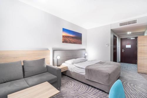 a hotel room with a bed and a couch at Hotel Leda Spa - Adults Only in Kołobrzeg