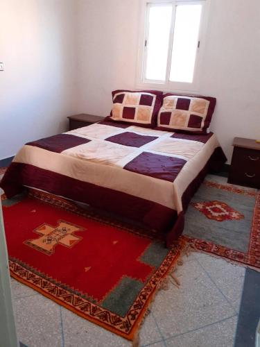 a bed in a room with rugs on the floor at Bel Appartement à El kelaa Des Srarhna in El Kelaa des Srarhna