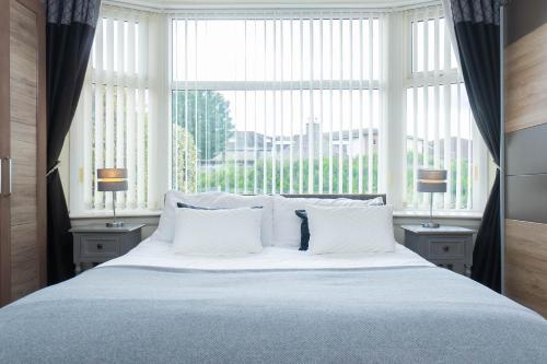 a large bed with white pillows in front of a window at Driveway Parking for 2 Vehicles, 3 Bedroom House, 2 Kings 1 Double, Garden, Fast WIFI, Ideal for Long Term Contractor, etc Stays, Regular Housekeeping Option - See Our Dwellcome Home Ltd Site for Assurance in Aberdeen