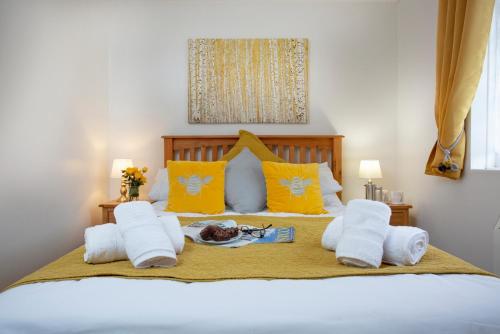 a bedroom with a bed with white towels and yellow pillows at Puffin Leigh Cottages in Seaton