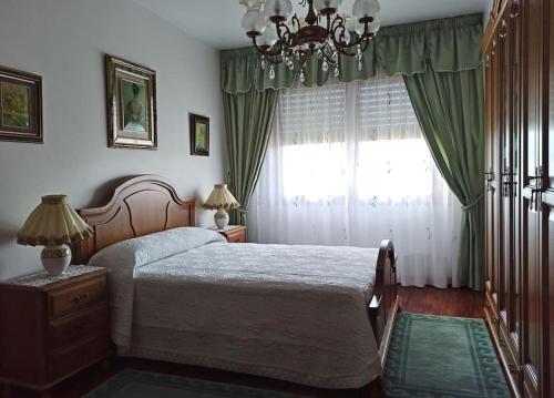 a bedroom with a bed and a chandelier and a window at Piso Amplio y Céntrico en Mugardos in Mugardos