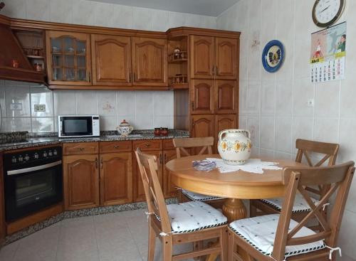 a kitchen with wooden cabinets and a table with chairs at Piso Amplio y Céntrico en Mugardos in Mugardos