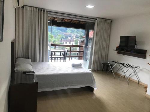 1 dormitorio con cama y vistas a un balcón en Casa com piscina e sauna em Petrópolis en Petrópolis