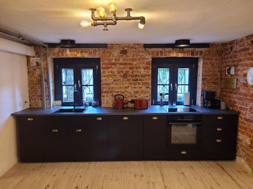 a kitchen with black cabinets and a brick wall at Apartment 22 in Coburg