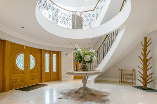 a vase of flowers on a table in a hallway with stairs at Scotsdale - exclusive family home in Ringwood