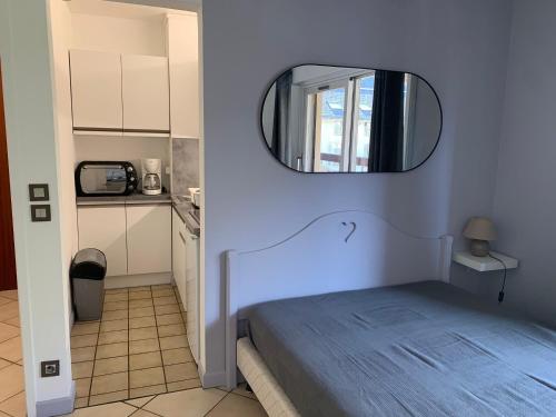 une chambre avec un lit avec un miroir au mur dans l'établissement Studio au cœur de Brides-les-Bains face au parc thermal, balcon, parking, idéal pour curistes et skieurs - FR-1-512-126, à Brides-les-Bains
