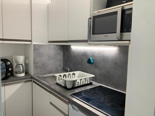 une cuisine avec un panier à vaisselle sur la cuisinière dans l'établissement Studio au cœur de Brides-les-Bains face au parc thermal, balcon, parking, idéal pour curistes et skieurs - FR-1-512-126, à Brides-les-Bains