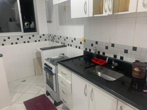 uma pequena cozinha com um lavatório e um fogão em PRAIA DA COSTA - 02 QUARTOS - SOL E MAR em Vila Velha