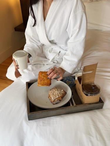 a woman sitting on a bed with a plate of food at The Francis Hotel in Portland