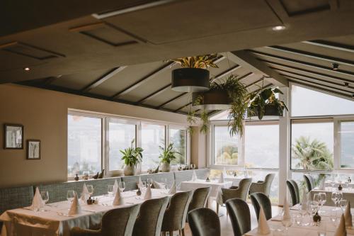 uma sala de jantar com mesas, cadeiras e janelas em Hotel Lisetta em Tirolo