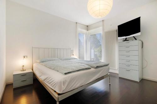 a white bedroom with a bed and a tv at Appartamento Sole Torbole in Nago-Torbole