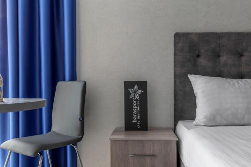 ein Schlafzimmer mit einem Stuhl und einem Bett mit blauen Vorhängen in der Unterkunft barasport city apartments in Kiew