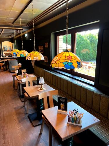 a restaurant with wooden tables and stained glass chandeliers at Lohmann's Kapeller Hof in Langenfeld