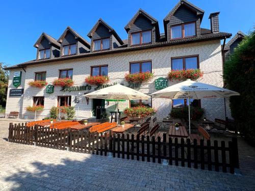 a restaurant with tables and umbrellas in front of a building at Lohmann's Kapeller Hof in Langenfeld