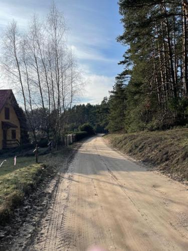 a dirt road next to a house and trees at Mazury Dom Oluś nad jeziorem Sasek Wielki z gorącą balia z funkcją jakuzzi in Szczytno
