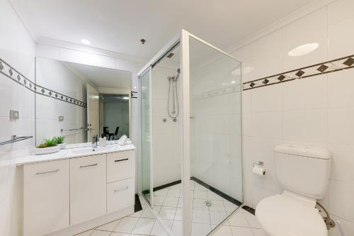 uma casa de banho branca com um chuveiro e um WC. em Comfy and Spacious 1B Sydney CBD Apartment in Central em Sydney