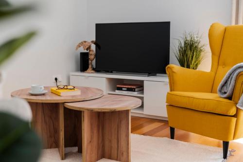 a living room with a tv and a table and a yellow chair at On the south coast of the island Ribeira Brava I in Ribeira Brava