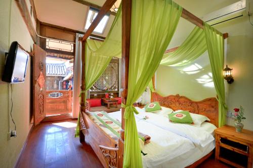 a bedroom with a canopy bed with green drapes at Lewo Guest House in Lijiang