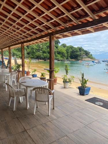 Praia VermelhaにあるPousada Frezza Mergulhoのビーチの景色を望むパティオ(テーブル、椅子付)
