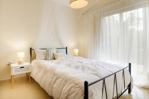 un grande letto bianco in una camera da letto con finestra di Marathon Luxury Suites - 2 bedroom a Schinias