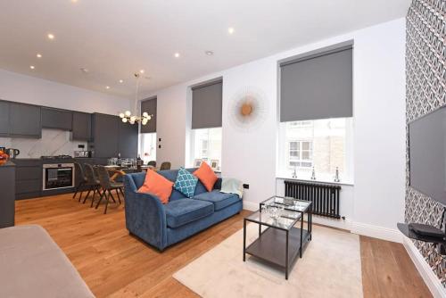 a living room with a blue couch and a kitchen at Sleep8 Buckingham Palace Bigben with AC VB4 in London