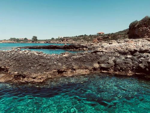 a pool of clear blue water next to a rocky shore at Villa Pantazi in Riglia