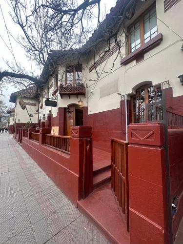 a red and white building with a fence next to a sidewalk at Maktub Montt - Hostal Boutique in Santiago